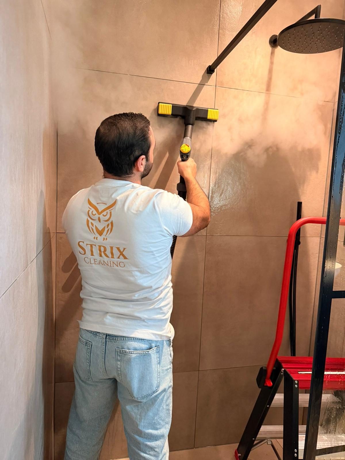 Schoonmaker van Strix reinigt douchewand met stoom