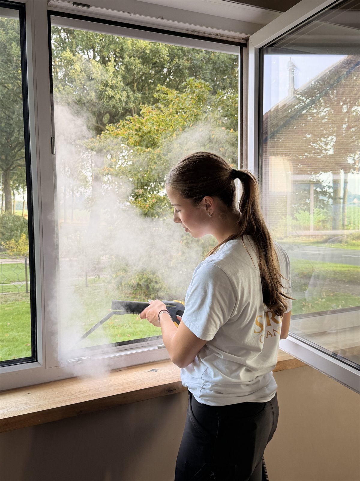 Medewerker van Strix Cleaning reinigt een raamkozijn met een stoomreiniger